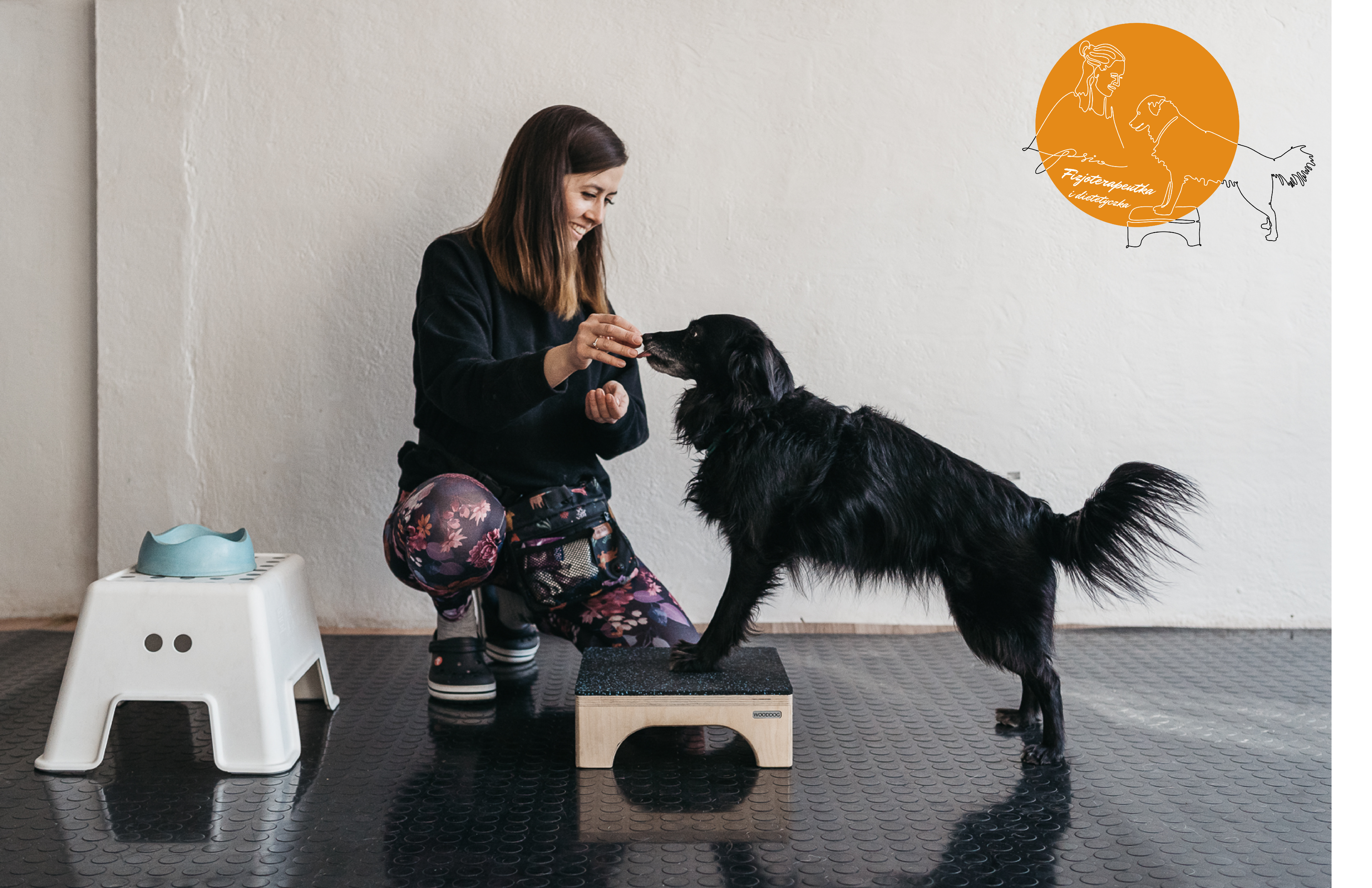 Zoofizjoterapeutka pracująca z czarnym psem podczas ćwiczenia równowagi, z miską i stopniem do rehabilitacji w tle i logo 'PsiaFizjoterapeutka' w rogu.